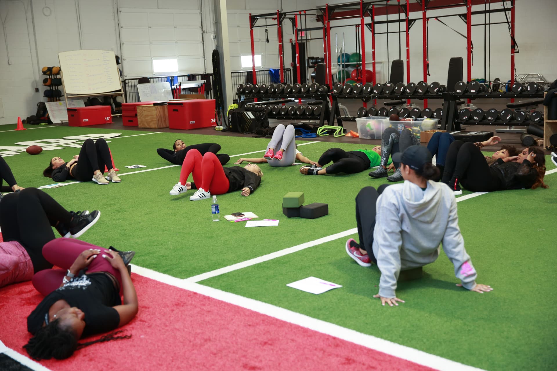 Full room of members doing floor work across the turf at the wellness session