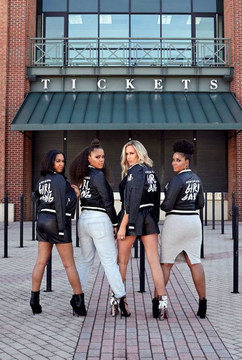 Four WAGS Redefined members in custom Girl Gang varsity jackets outside a stadium ticket entrance