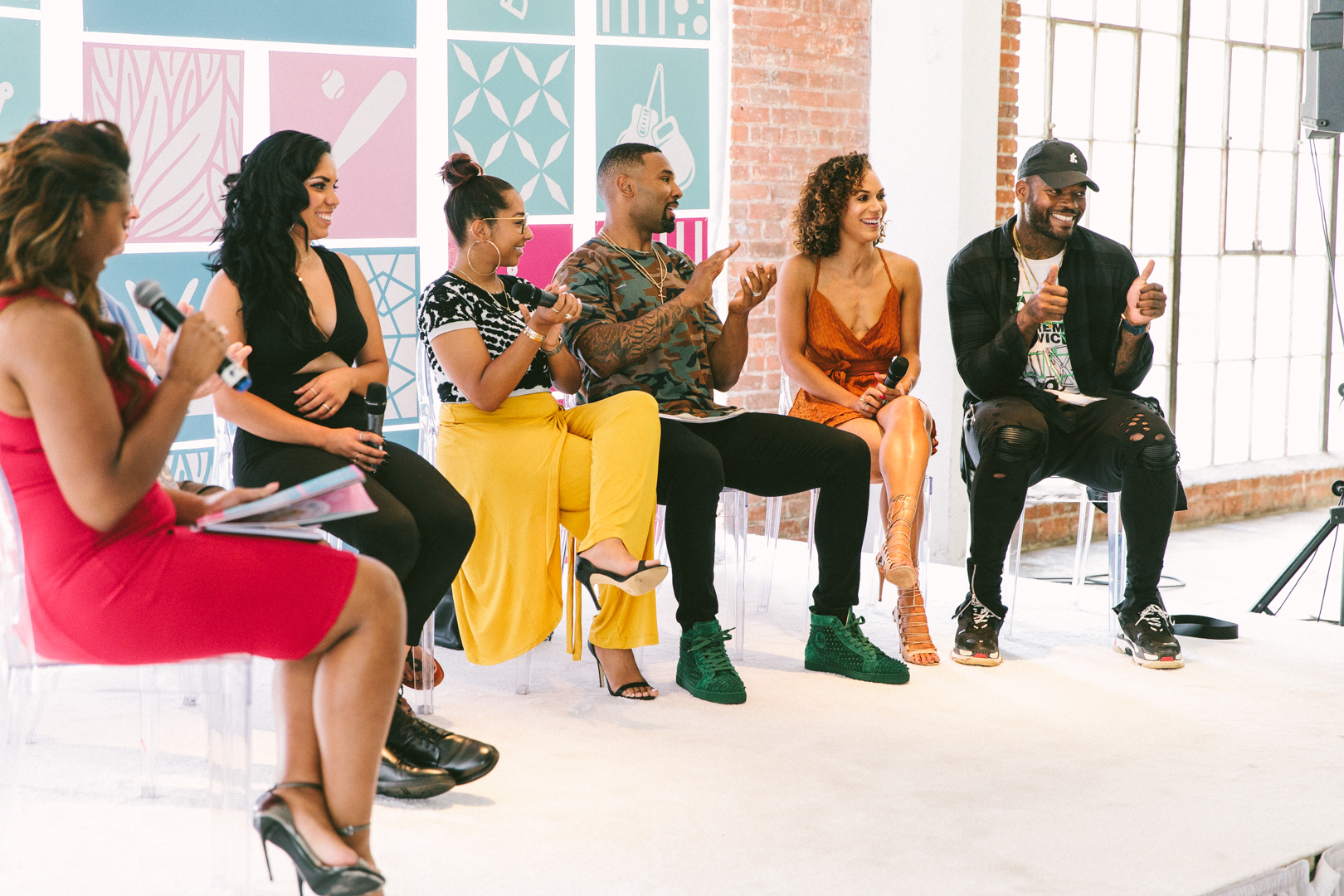 WAGcademy panel of athletes and partners mid-conversation in front of the branded mural