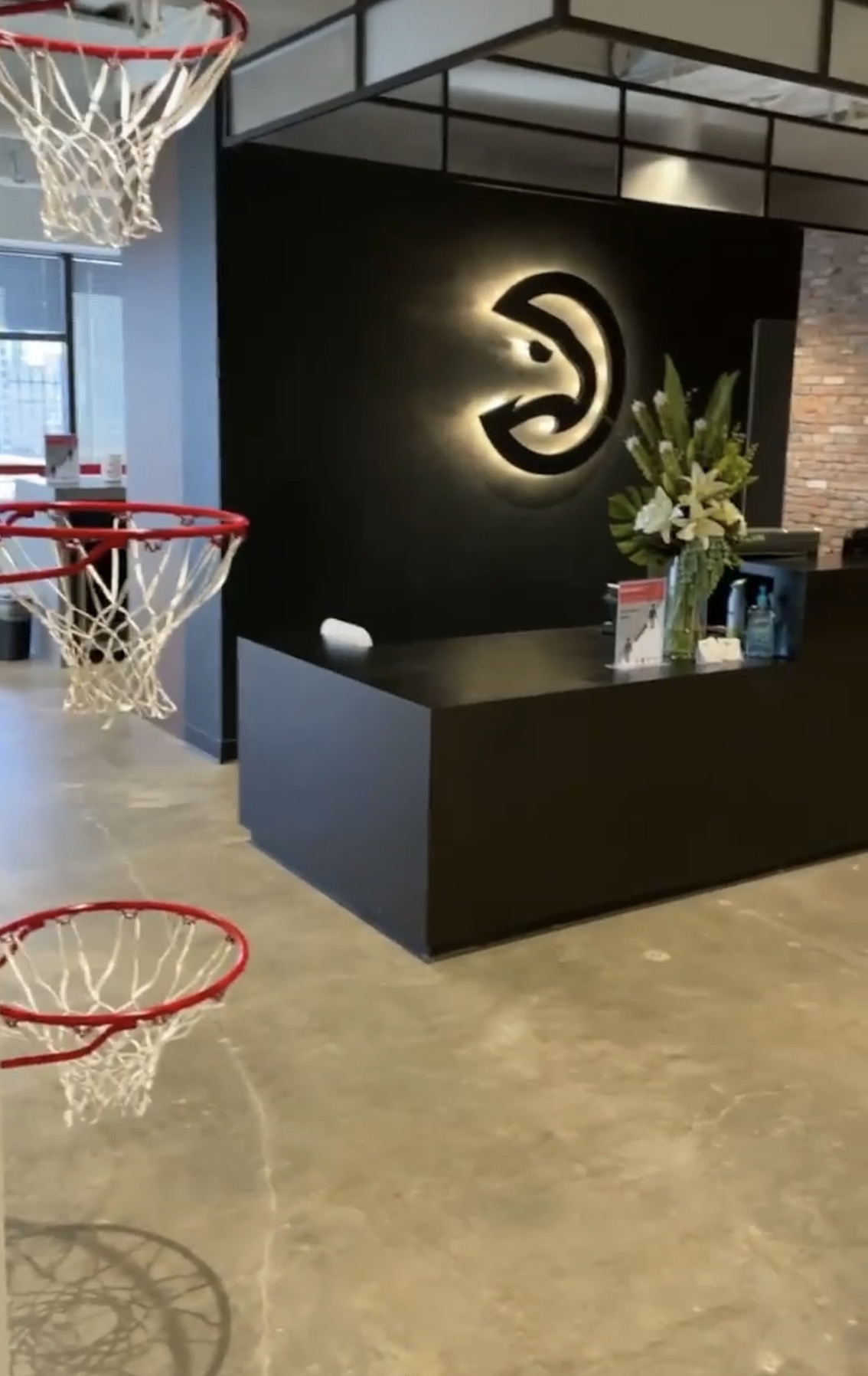 Atlanta Hawks front office lobby with a backlit logo wall and basketball hoops hanging from the ceiling
