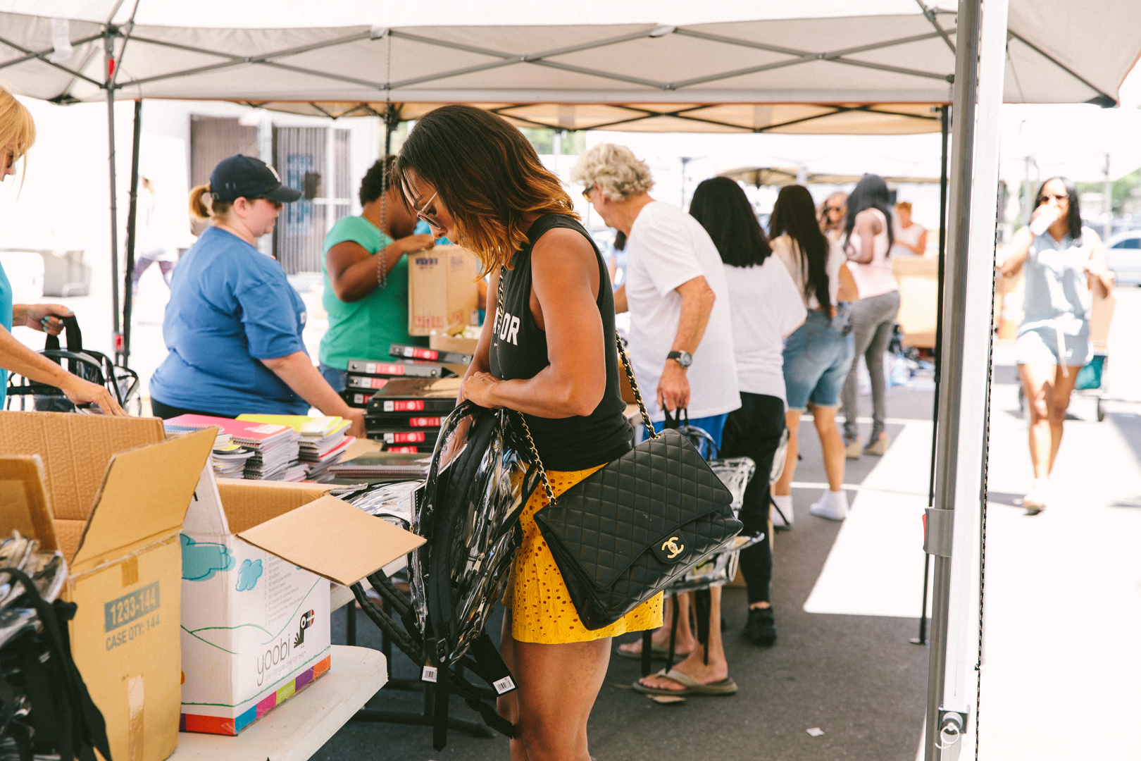 Volunteers working the supply tables under canopies at the back-to-school drive