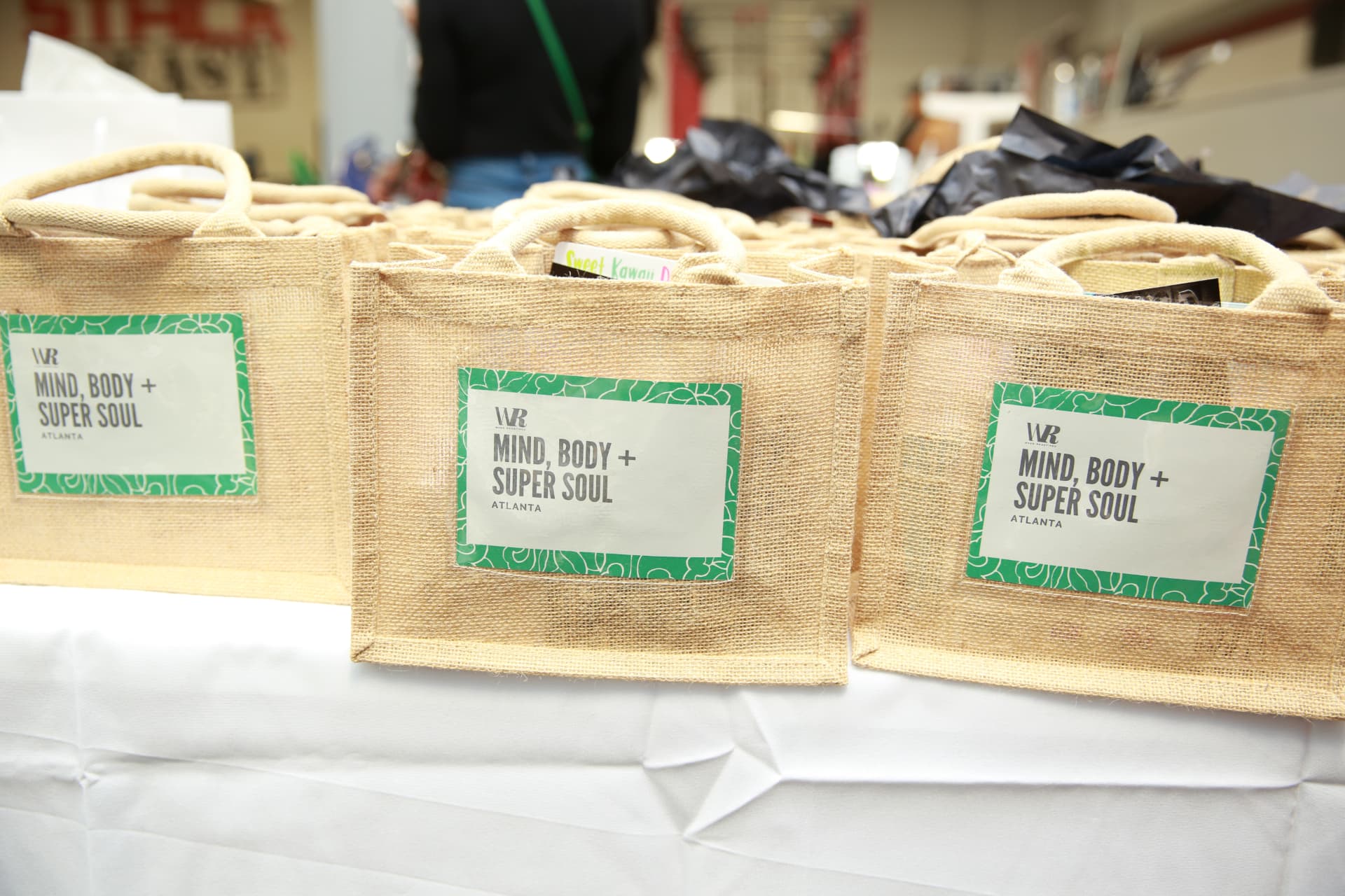 Row of burlap Mind, Body + Super Soul Atlanta gift bags on the welcome table