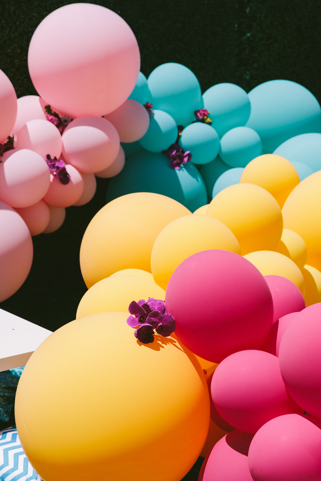 Pink, teal, yellow and magenta balloon installation with orchid accents on the rooftop turf