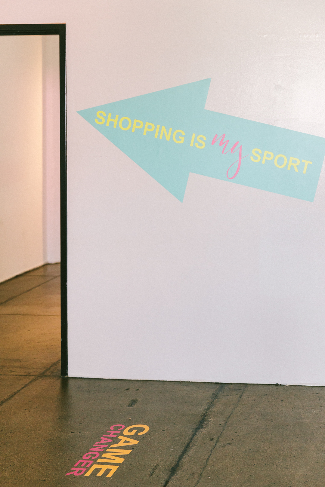 SHOPPING IS MY SPORT wall arrow pointing into the styling suite, with a GAME CHANGER decal on the floor