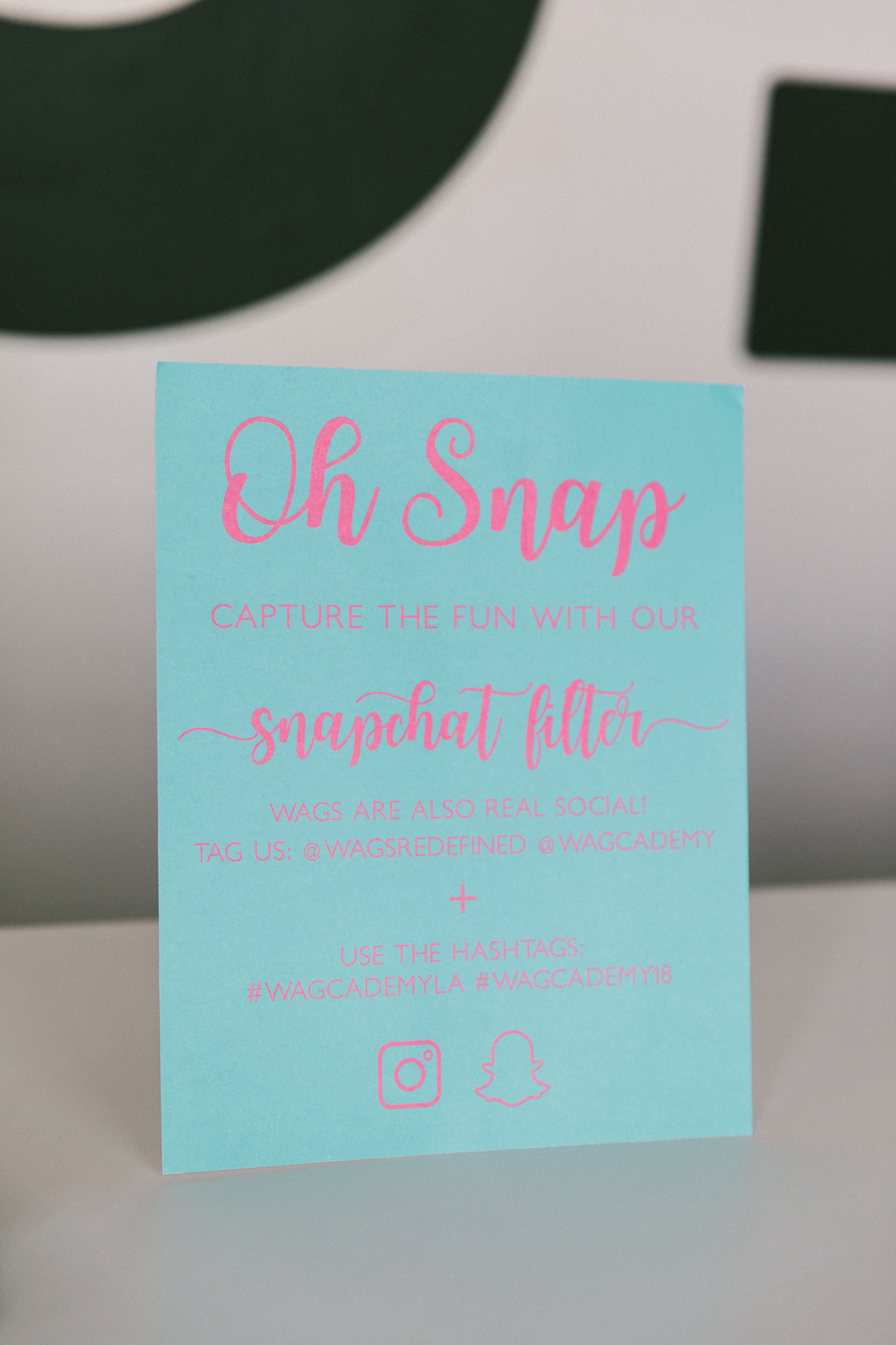 Oh Snap card at check-in inviting guests to use the WAGcademy Snapchat filter and hashtags