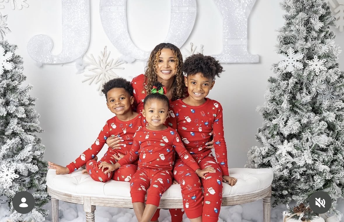 LeLe Martin with her three sons in matching red holiday pajamas in front of a JOY backdrop