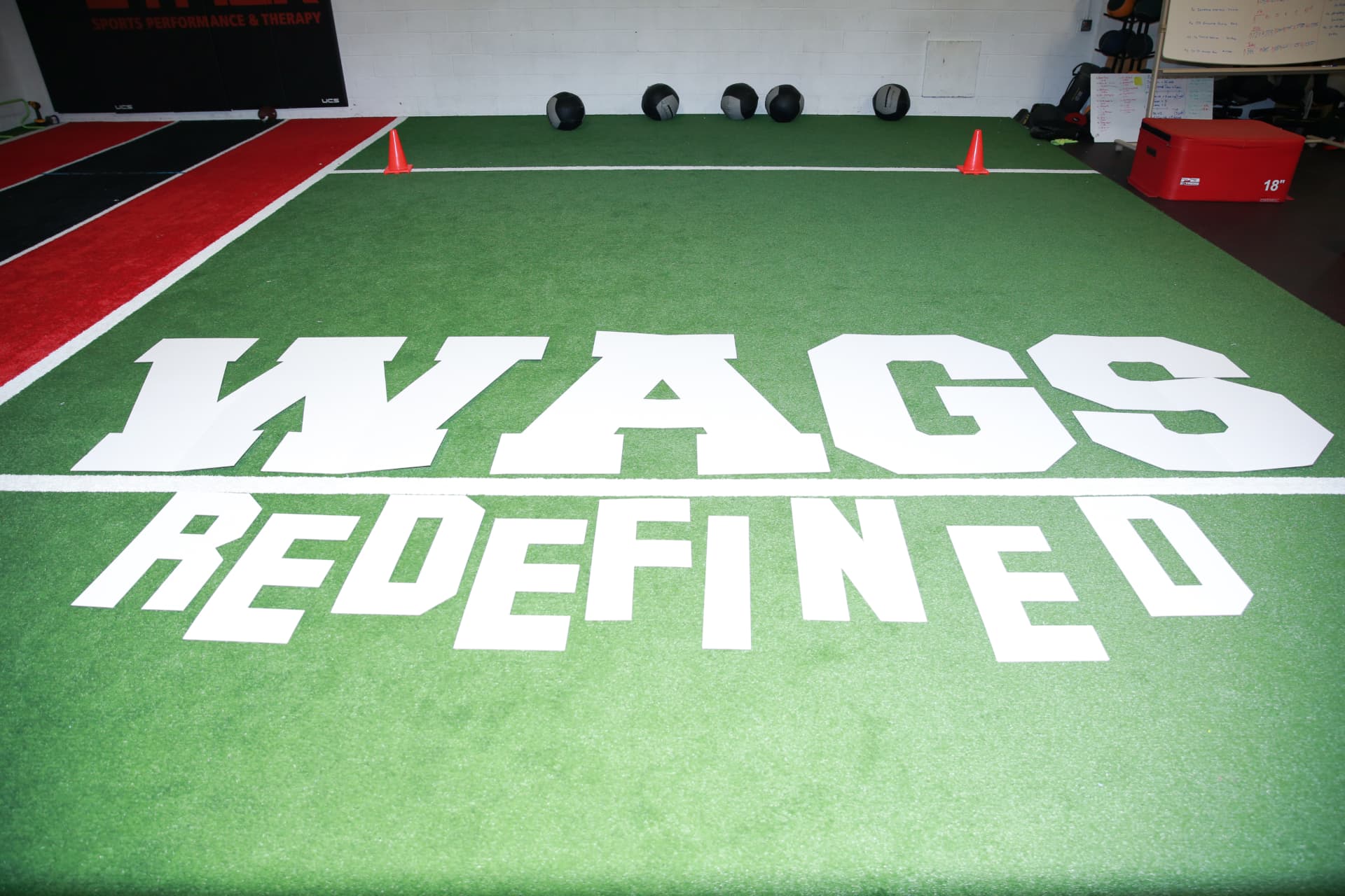 WAGS Redefined lettering laid out on the turf at STACK Sports Performance