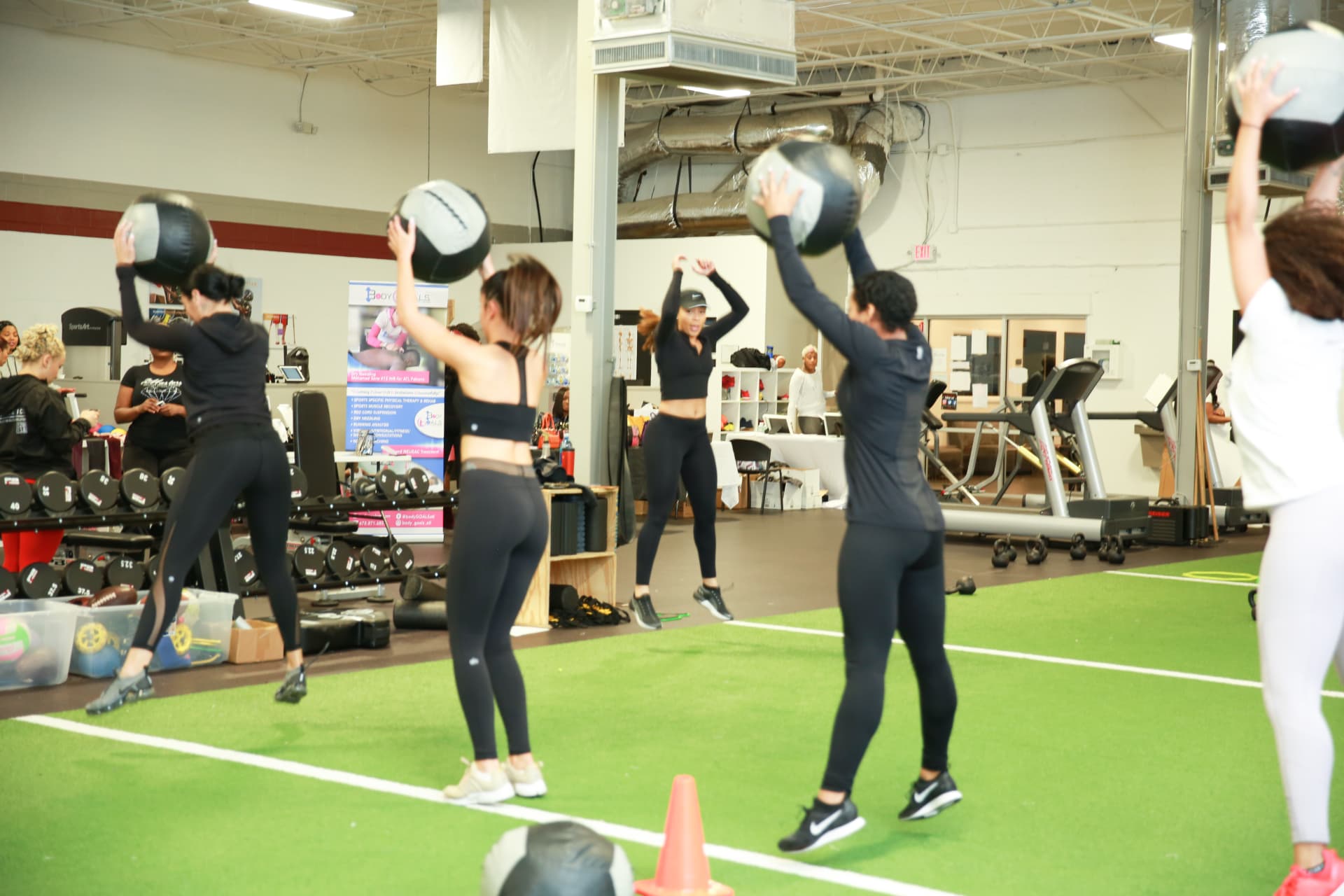 Members working through a medicine ball circuit on the turf during the training session