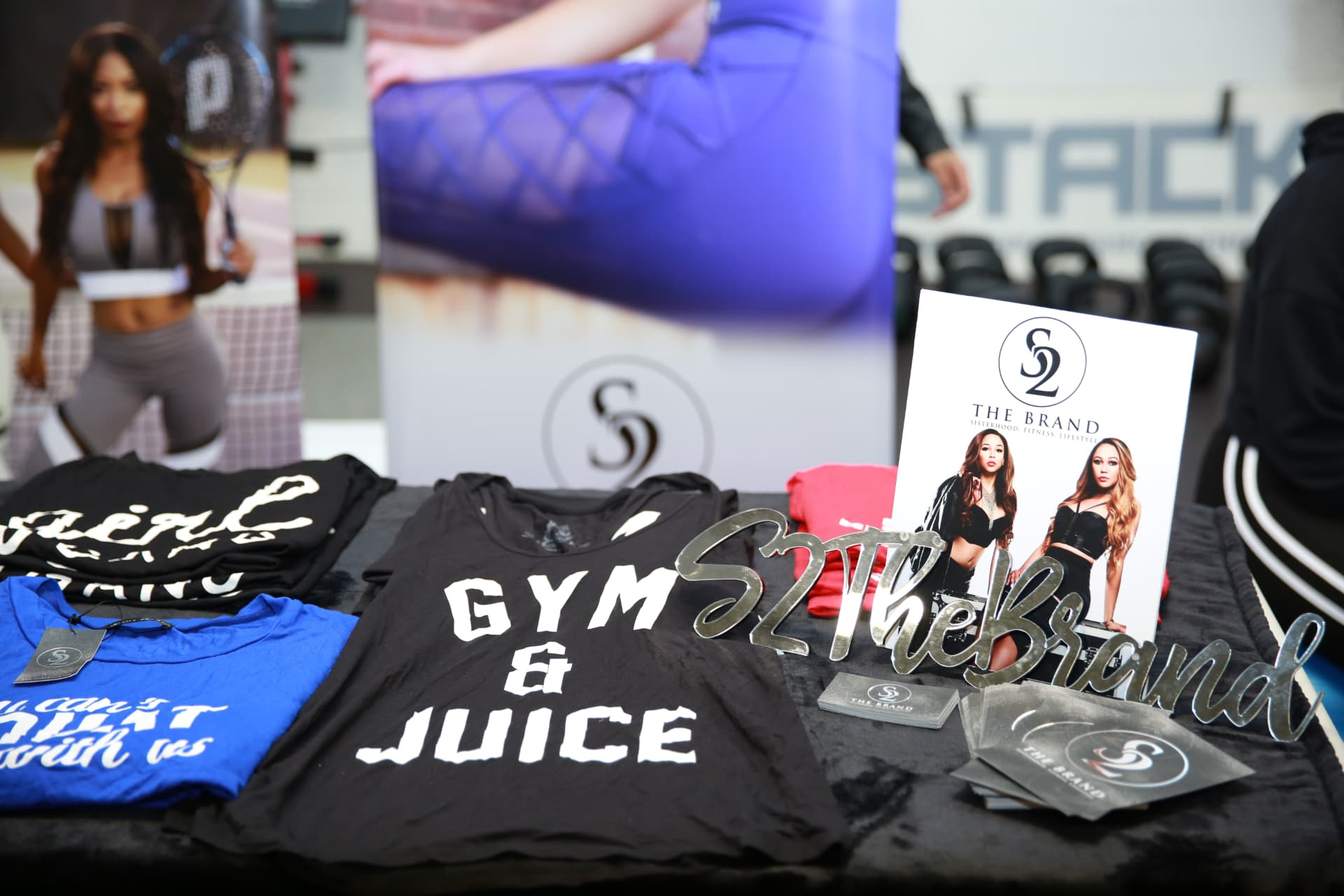 S2 The Brand Gym & Juice tees laid out beside the mirrored brand signage