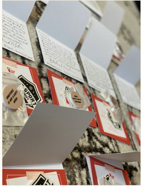 Handwritten Sport Sorority welcome cards laid out with membership goal inserts, logo stickers and Ambitious Is Not A Dirty Word buttons